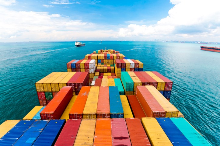 Series 1 freight containers following ISO 668:2020 and piled on barge at blue sea.