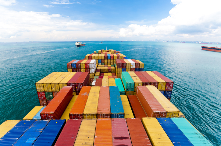 Series 1 freight containers following ISO 668:2020 and piled on barge at blue sea.