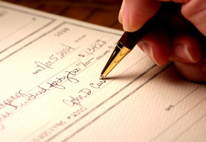 Signing a check with a gold pen to generate an ANSI X9.100-160-2-2020 MICR external processing code (EPC).