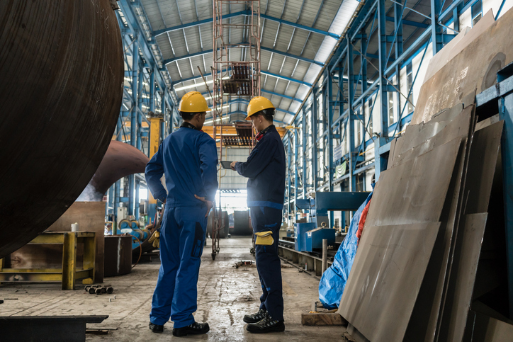 Diligent factory workers discussing the changes to ISO/IEC 17000:2020 and how they can meet conformity assessment