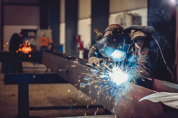 Welder welding while following the guidelines set by AWS D1.1