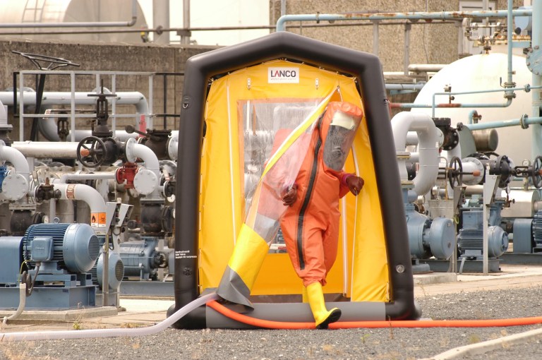 Doctor suited up stepping out of an ANSI/ISEA 113 decontamination shower.