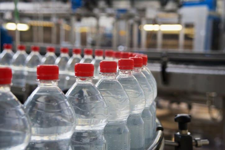 Plastic water bottles looping through factory conveyor belt marked to ISO 11469:2016