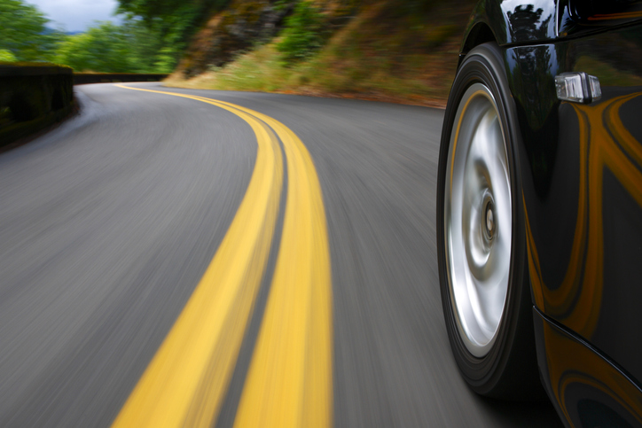 Black sports car speeds in landscape that blurs like a painting with wheels tested to SAE J 175-2021 for lateral impact