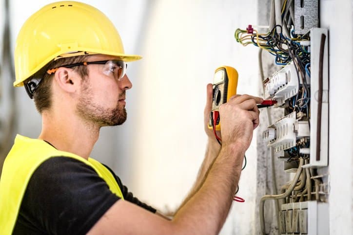 Man in yellow hardhat testing wiring system with the National Electrical Code (NEC), or NFPA 70-2017