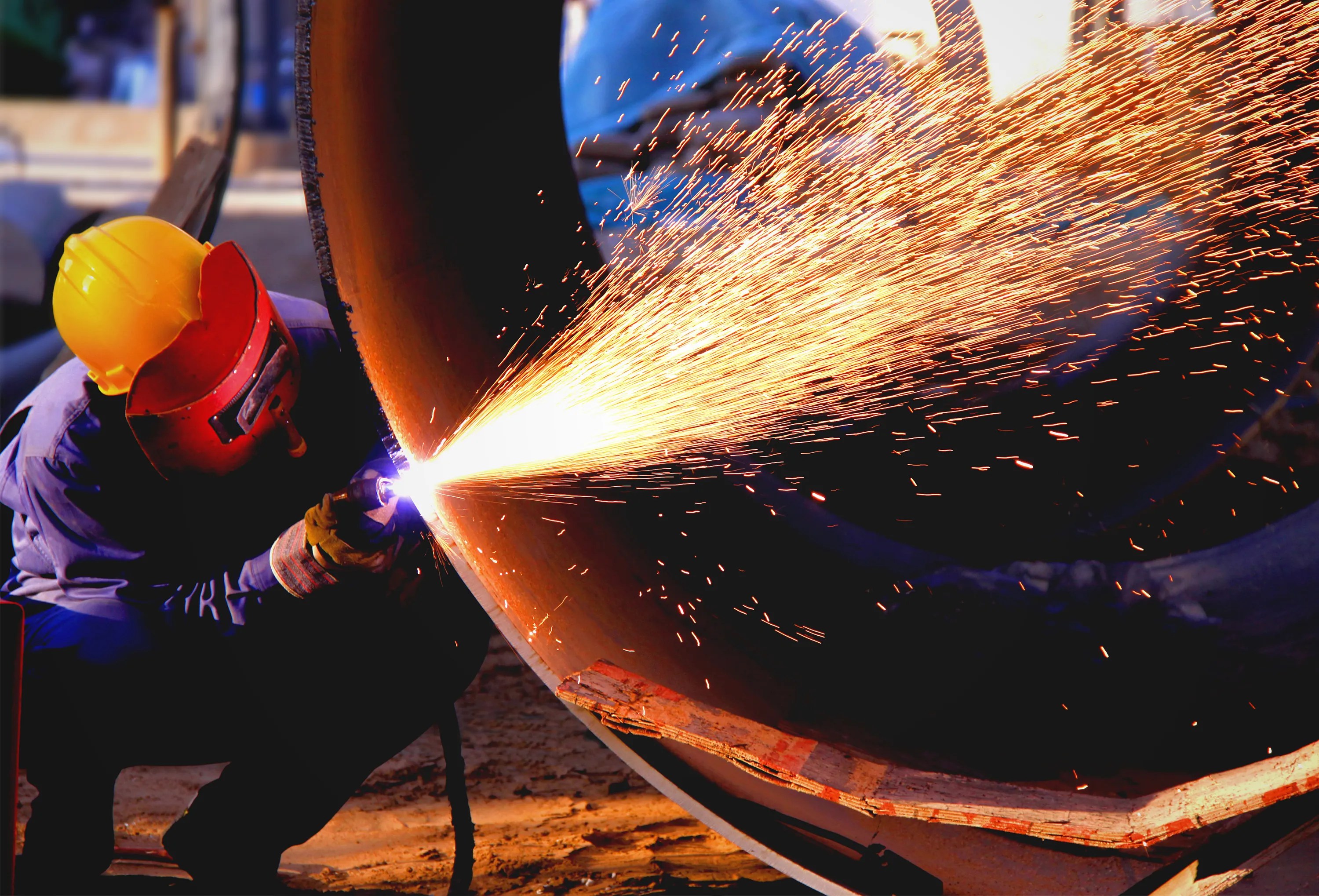 Welder shooting sparks while working on steel pipeline flanges with ANSI/MSS SP-44-2026