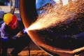 Welder shooting sparks while working on steel pipeline flanges with ANSI/MSS SP-44-2026
