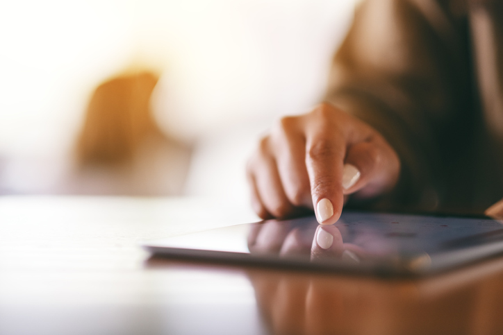 Woman sliding finger across tablet in a gesture based interface according to ISO/IEC 30113-1.