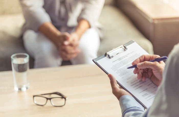 Checking the boxes on a clipboard to evaluate, via ANSI/IESNA RP-29-20, the effects illuminating health care spaces can have on health.