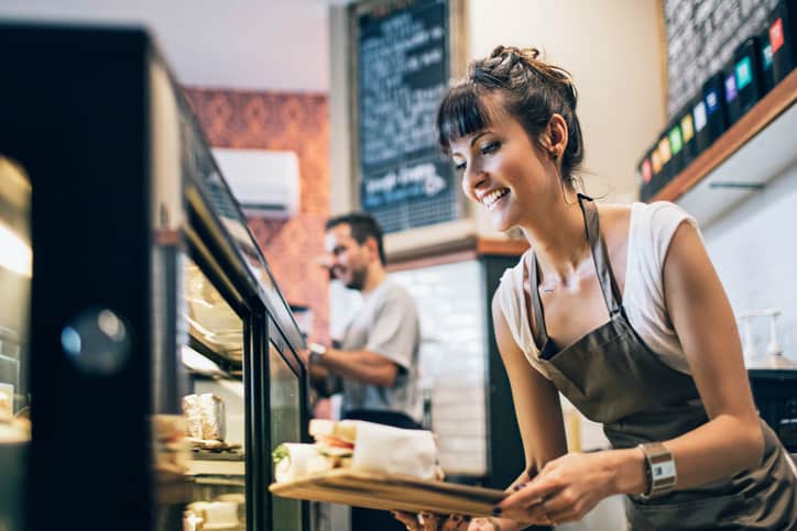 Woman working at a deli, making quality sandwiches and knowing what to do thanks to ISO 9001:2015 for Small Enterprises.