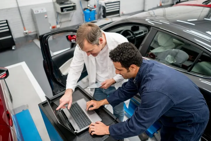 Two workers in garage depending on the AIAG CQI-20:2018 Problem Solving Guideline.