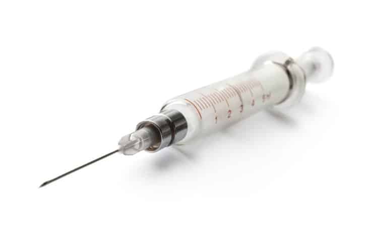 A plain white ISO 7846:2016 hypodermic needle, kept sterile and ready for use.