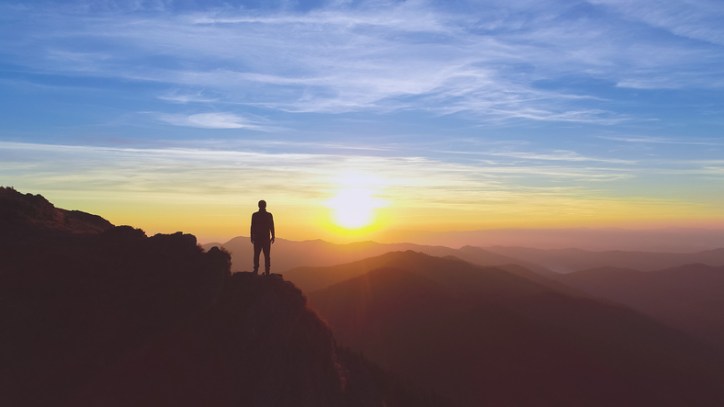 Man gazing at the sunrise in nature thanks to ISO 14000 standards and ISO 14065 greenhouse gas accreditation.