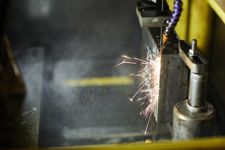 An electro discharge machine (EDM) is sparking in action with ANSI B11.27-2020 safety requirements in factory.