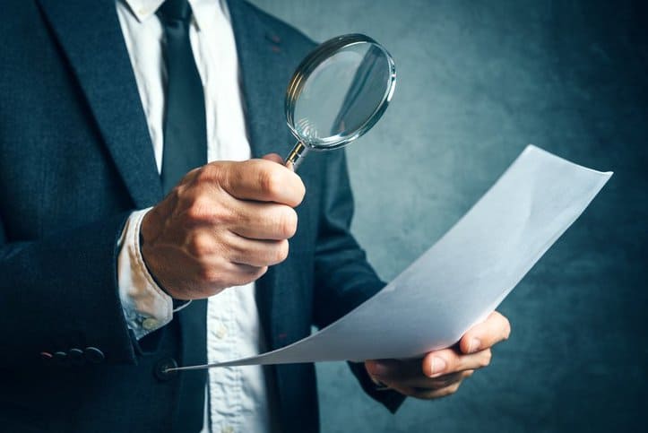 Man in suit inspecting a document forensically.