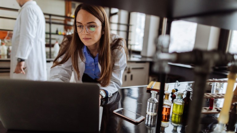 Female lab technician on a computer to complete remote assessment and finish her ANAB laboratory accreditation.
