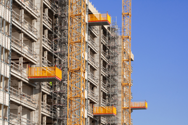 Some yellow ANSI/ASSP A10.5-2020 material hoists carefully installed to transport construction equipment and personnel.