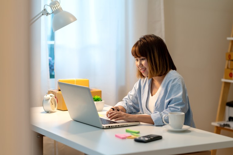 Woman happy yet inquisitive on laptop while going through ANAB live online management systems training.