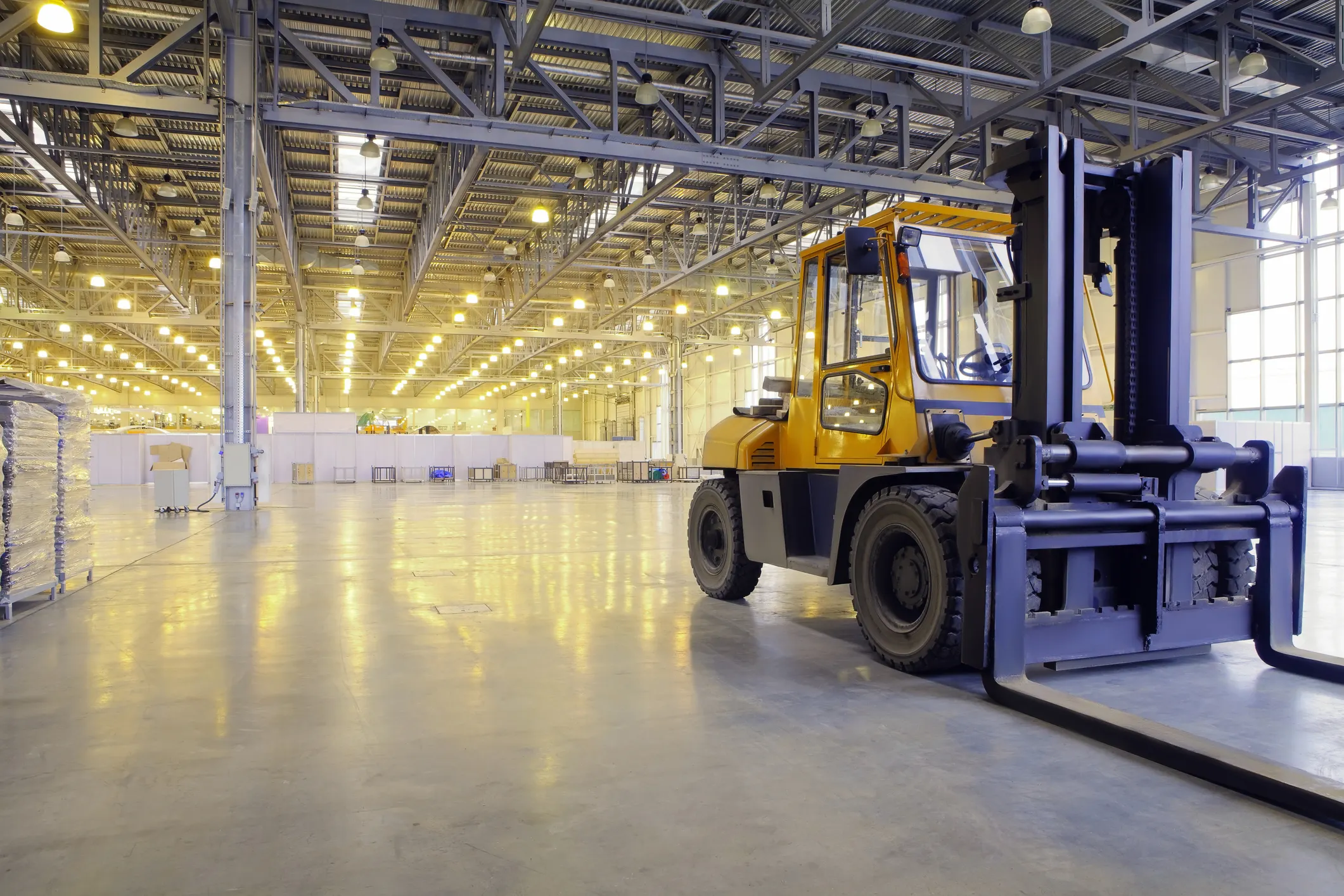 Bright yellow industrial low-lift truck ready for work in warehouse with ANSI/ITDSF B56.1 help.