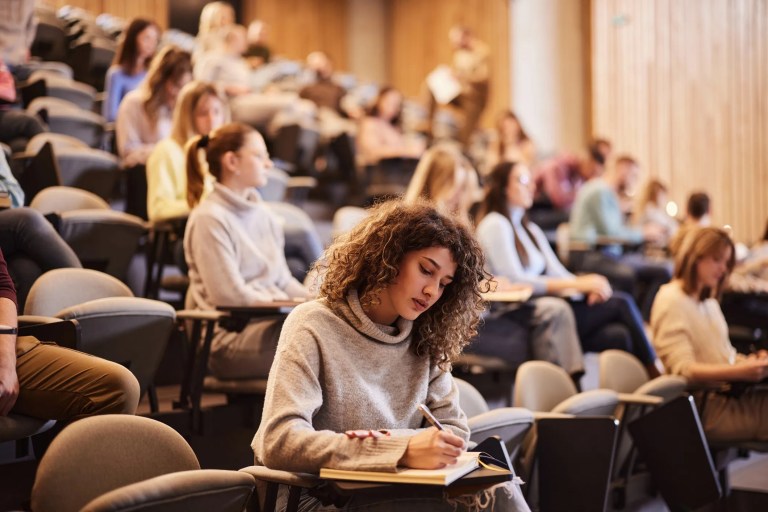Students taking notes in a college classroom.
