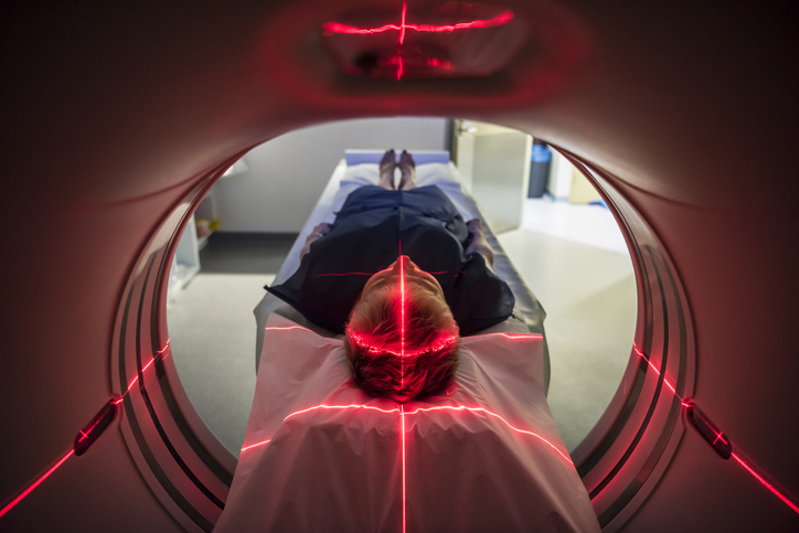 Patient undergoes red light of PET scan and CAT scan technology refurbished to IEC 63077 medical imaging requirements.