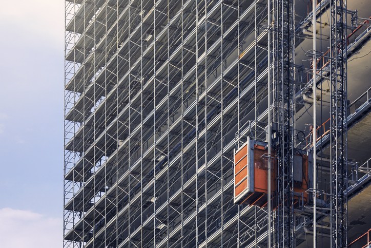 Hoist elevators that follow ANSI/ASSE A10.4-2016 on the side of a building in the process of being constructed.