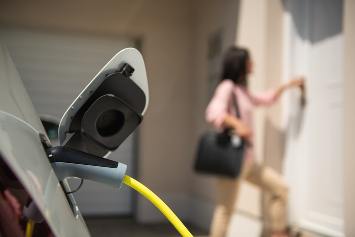 Businesswoman returning home and charging electric vehicle overnight, as the EV exceeded her expectations.