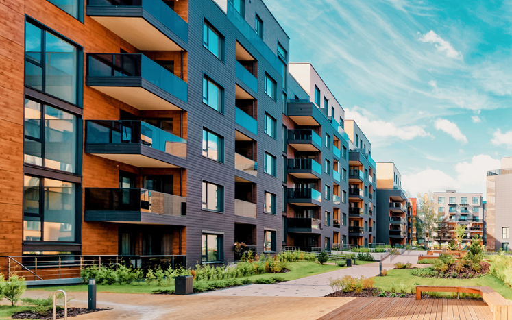 A multifamily building with verdant greenery assured to safety with ANSI/AARST MAMF-2017 radon measurements.