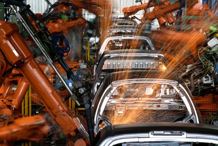 Robot arms manufacturing automobiles in compliance with IATF 16949 and ANAB accredited laboratories.