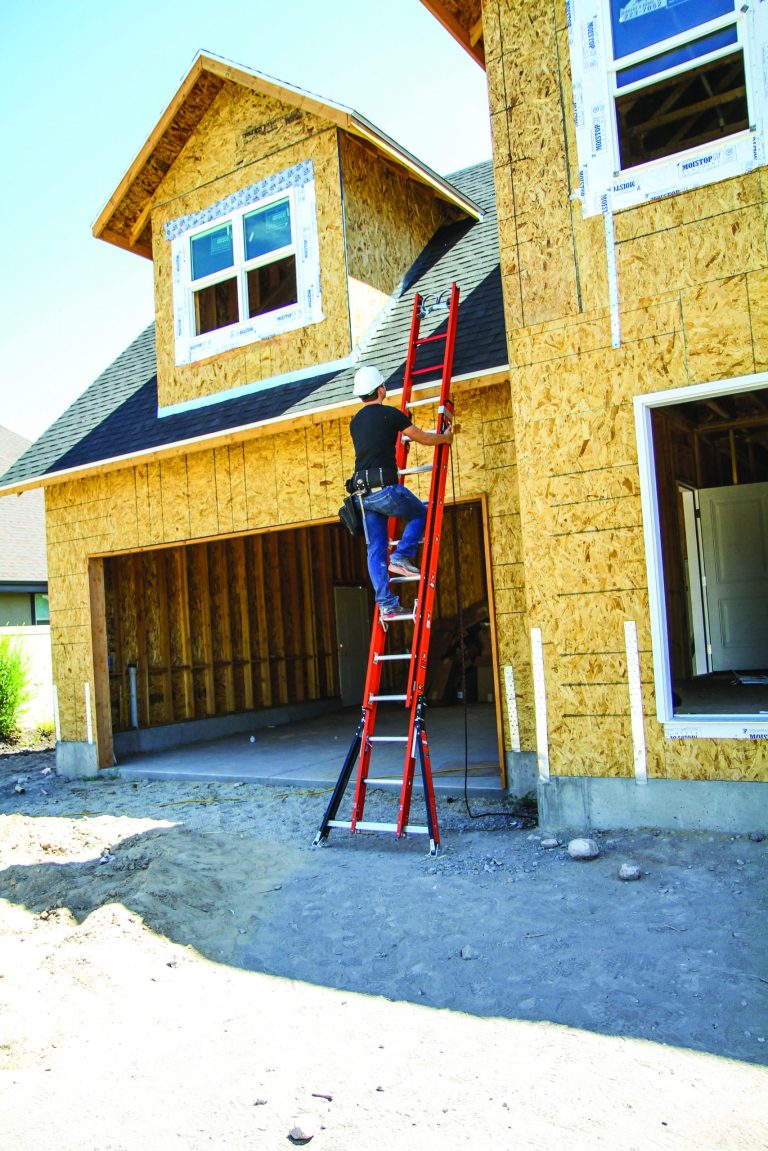 Construction worker climbing red metal extension ladder with three points of contact and basic safety tips.