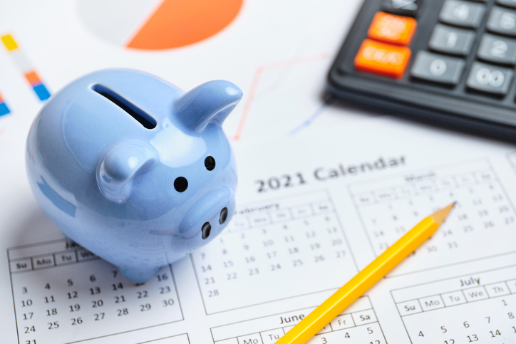 Blue piggy bank on 2021 calendar for financial planning of ASTM E2659 accredited certificate issuer programs.