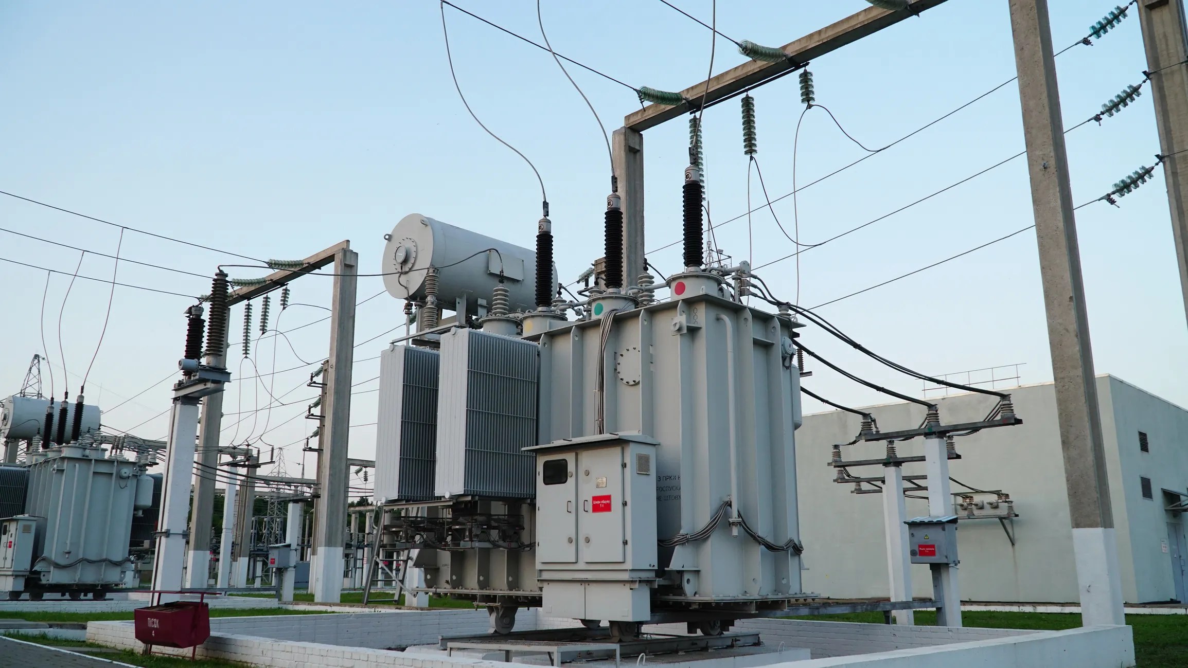 Gray electrical power transformer tested to ANSI/NETA ATS-2025 beneath blue sky