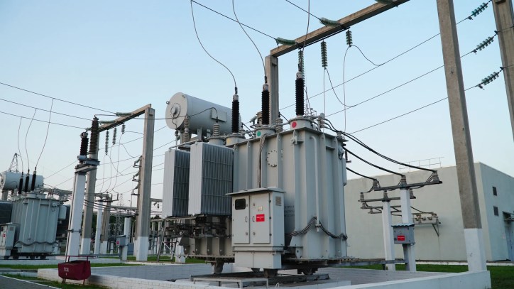 Gray electrical power transformer tested to ANSI/NETA ATS-2025 beneath blue sky