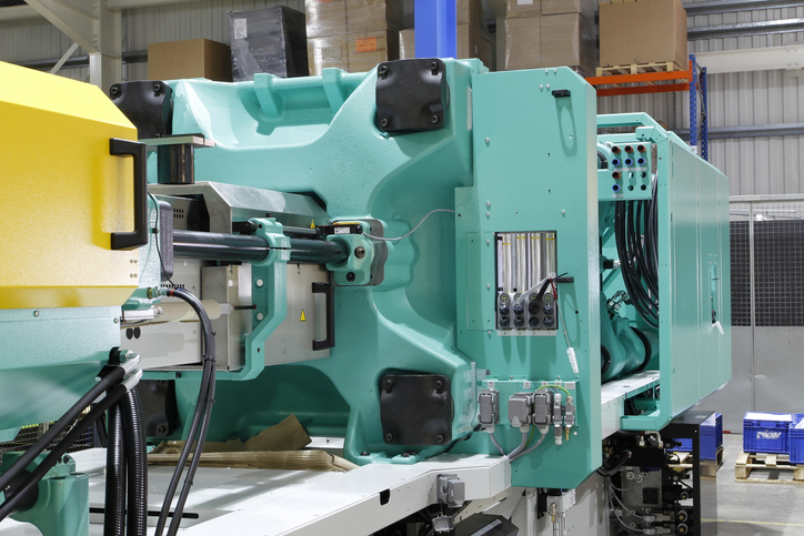 A green injection molding machine using robots kept safe by ANSI/PLASTICS B151.27-2021 safety requirements.