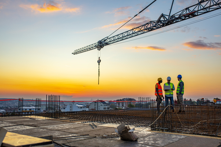 Construction workers in HVSA discussing the 2020 OSHA Top 10 List of Cited Violations under sunset crane.