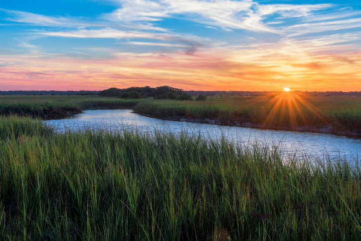 Sunset over river and greenery from adherence to ISO 14065 for greenhouse gas validation/verification body accreditation.