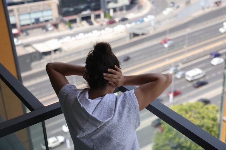 A woman covering her ears due to loud noise pollution.