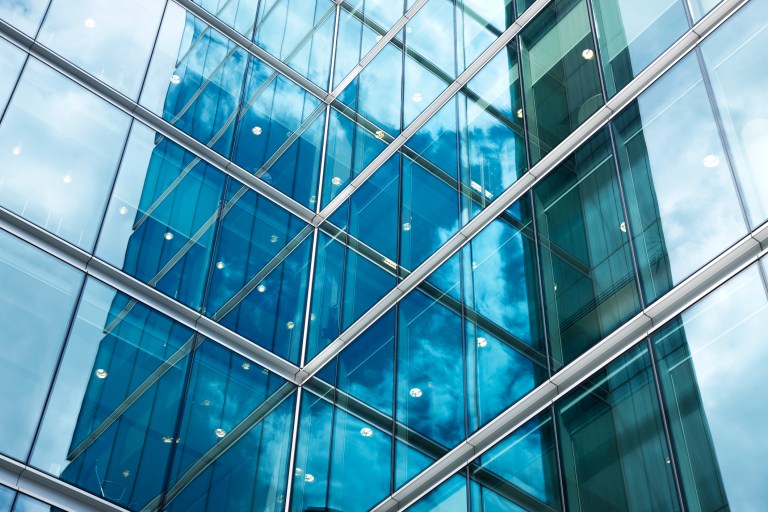 Flat glass exterior of blue corporate building that has been quality tested to ASTM C1036-21.