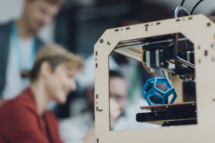 Group in background formatting ISO/ASTM 52915:2020 additive manufacturing file format (AMF) to print blue hexagon.
