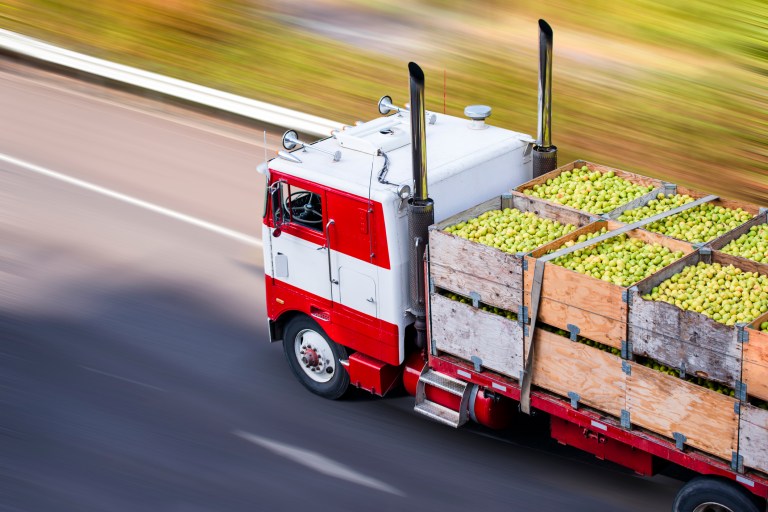 Red old fashioned semi truck lugging pears across the United States thanks to ANAB food safety credentialing accreditation.