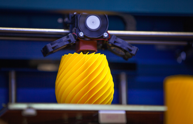 A yellow spiral object being 3D printed according to ISO/ASTM 52900 terminology.