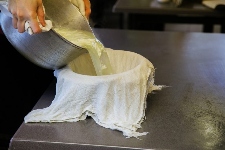 Pouring paneer cheese into cheesecloth.