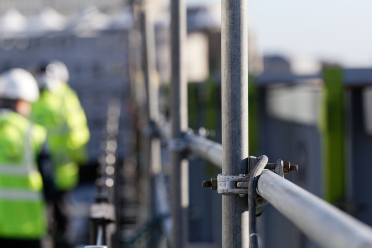 Steel scaffolding of construction site at height that workers need ANSI/ASSP Z359.14-2021 self-retracting devices.