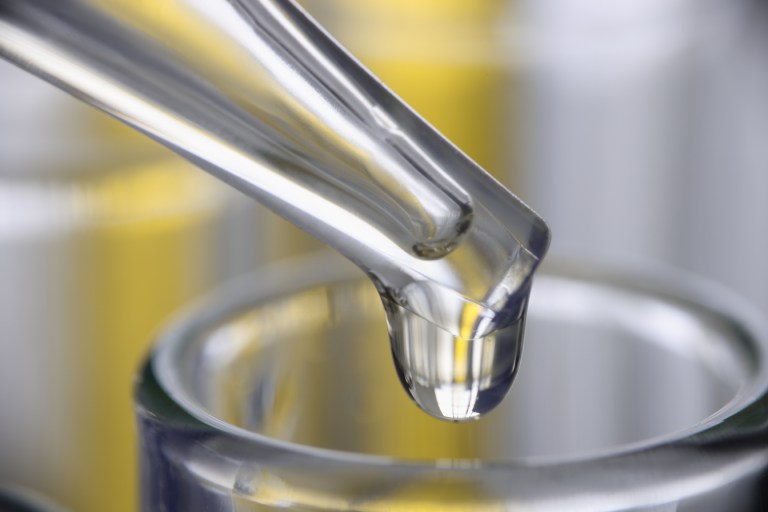 Liquid dripping from pipette as worker tests in standalone sampling organization laboratory.