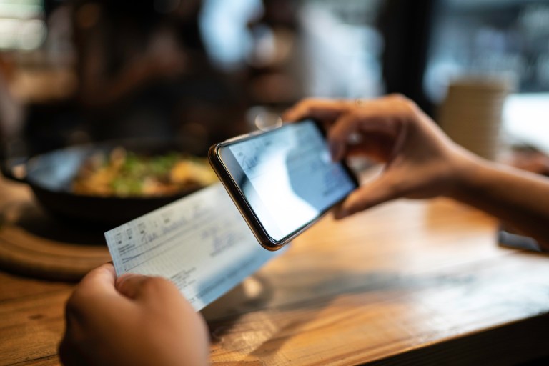 Man making mobile check deposit through app assured with ANSI X9.100-187-2021 provisions.