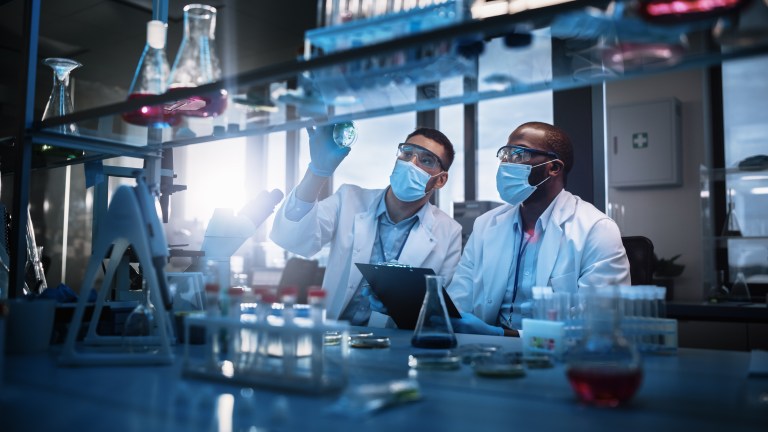 Assessor conducting reaccreditation of a lab beside other masked lab employee.