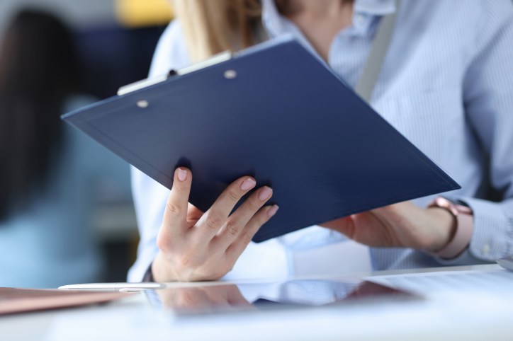 Woman reviewing clipboard during an ASTM E2659-18 internal audit of a certificate program.