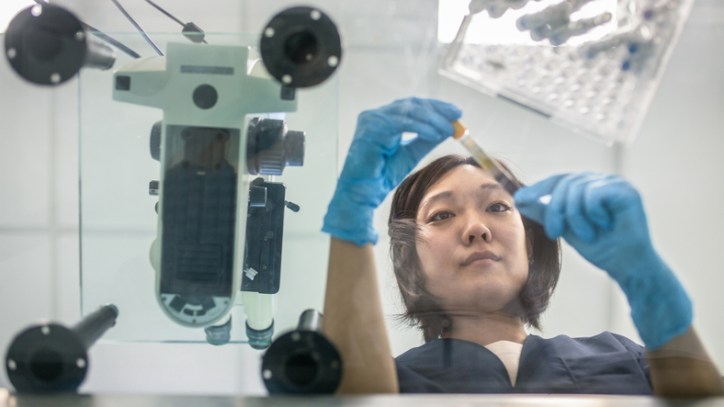 Lab technician examining test tube for adherence to ISO 15189 to prepare medical laboratory for accreditation.
