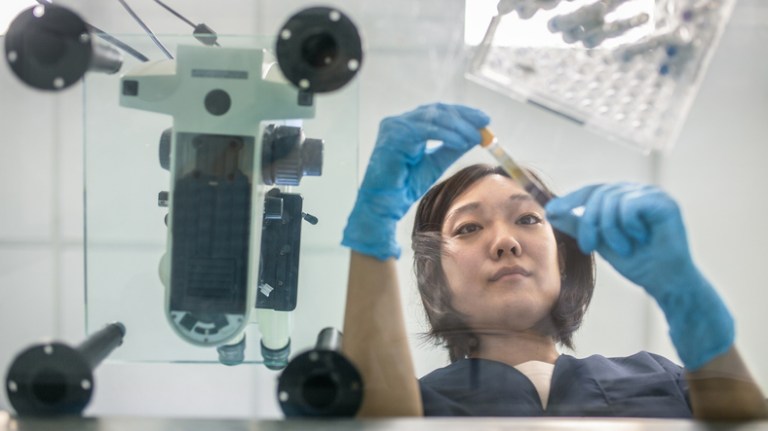 Lab technician examining test tube for adherence to ISO 15189 to prepare medical laboratory for accreditation.