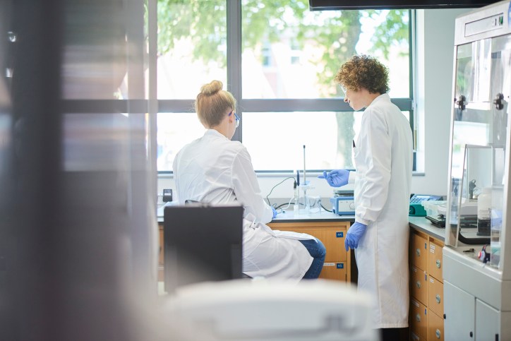 Geneticists working in ANSI/ASSP Z9.5-2022 ventilated lab in front of tree filled window.